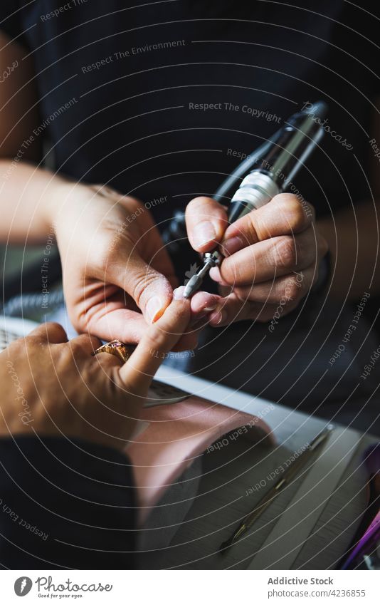 Anonyme Meisterin poliert die Nägel einer Kundin mit einer elektrischen Feile Frauen Maniküre nageln Aktenordner Verfahren Schönheit Leckerbissen Arbeit