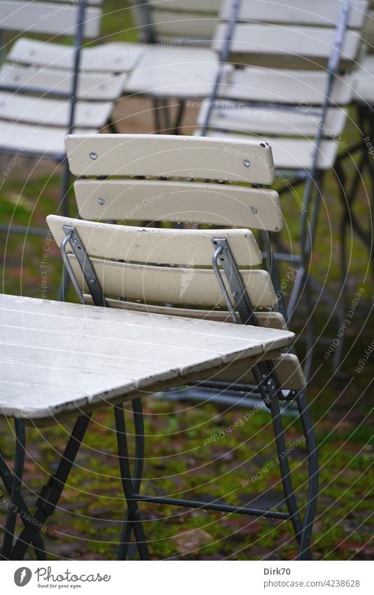 Gartenstuhl im Regen, zusammengeklappt Stuhl nass Biergarten biergartengarnitur biergartenmöbel Tisch Gartentisch stühle draußen Gastronomie Menschenleer