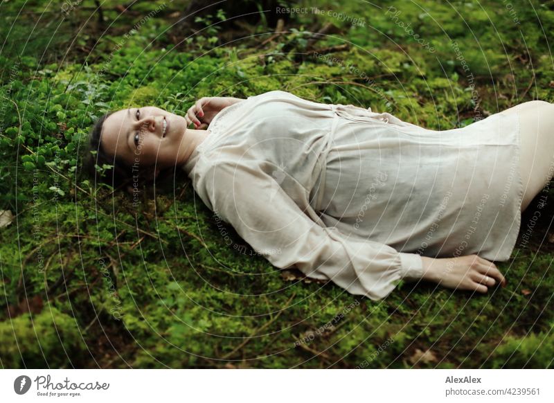 Junge Frau liegt auf Moos im Wald auf einer Lichtung Junges Fräulein Boden Waldboden schoen anmutig brünett hübsch 18-30 Jahre 30-45 Jahre langhaarig kleid