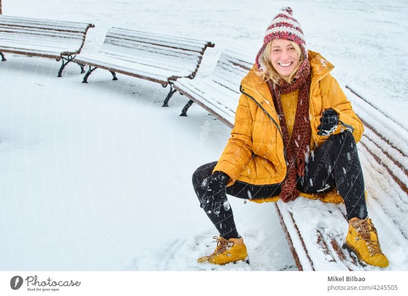 Kaukasische junge Frau sitzt auf einer Bank genießen Schnee im Freien im Winter Zeit. Lifestyle Menschen Lebensstil Wetter charmant Glück Gefühle Kaukasier