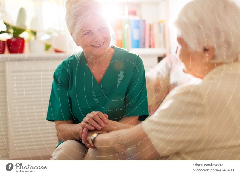Krankenschwester tröstet ihre ältere Patientin, indem sie ihre Hände hält Menschen Frau Senior reif lässig Kaukasier heimwärts Haus Pflege alt Gesundheit