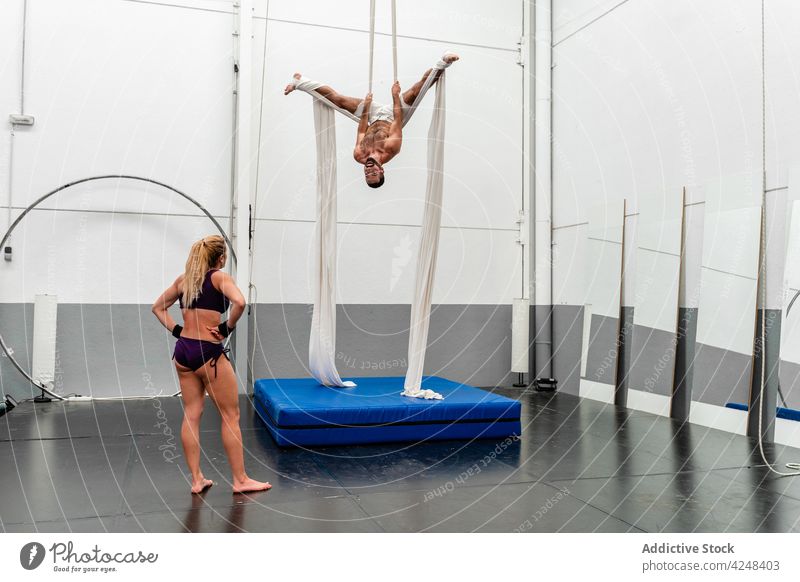 Sportlerin schaut auf eine flexible Freundin, die Übungen auf dem Luftseil ausführt Antenne Seide ausführen sportlich Training auf den Kopf gestellt