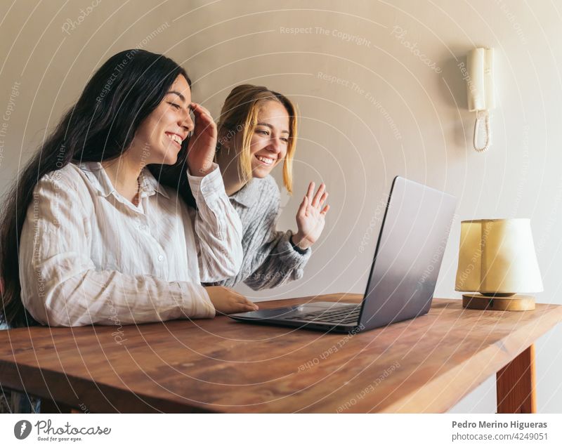 zwei Frauen Freunde winken, während auf Videoanruf Laptop Lifestyle Internet Sitzen Computer Glück Zusammensein Paar Liebe heimwärts jung online