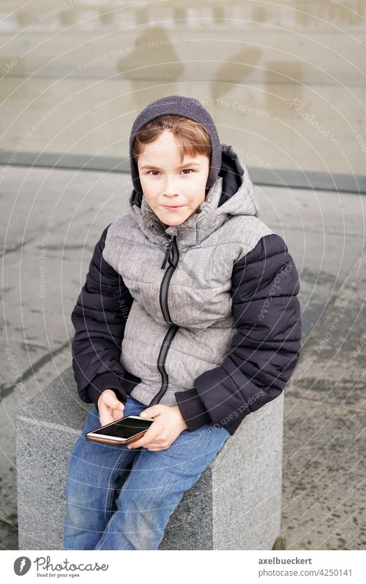 7 Jahre alter Junge mit Smartphone im Freien im Winter Kind spielen Technik & Technologie Spiel Internet Lifestyle jung Kindheit Person Kaukasier Drahtlos