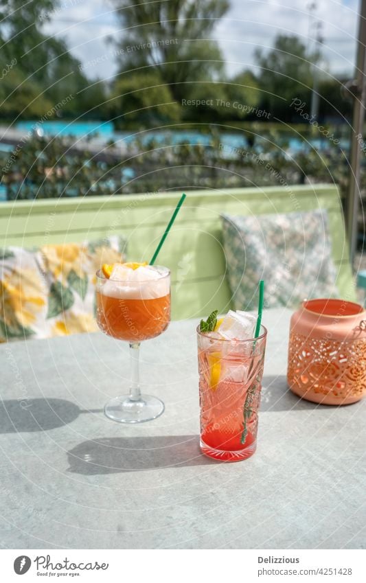 Pinke Cocktails, die draußen auf einer sonnigen Terrasse mit Swimmingpool im Hintergrund serviert werden trinken jubelt Essen und Trinken Genießer Bar Sommer
