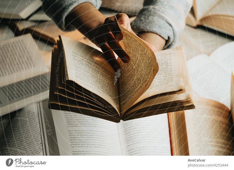 Nahaufnahme eines Paars schwarzer Hände, die ein altes Buch mit Kopierraum über einem Bündel von Büchern lesen Bildung Person Bibliothek Literatur offen Page