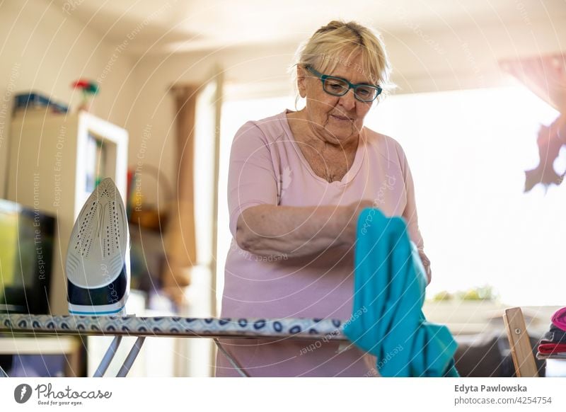 Ältere Frau zu Hause bügeln Kleidung Brille Falte natürlich echte Menschen lässig Tag Lifestyle Großmutter Rentnerin gealtert Freizeit Ruhestand Lebensalter