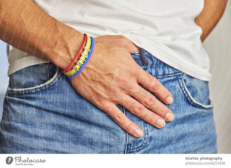 Männliche Hand mit Regenbogen-Armband und Text Stolz in der Tasche der Jeans Stolz-Monat Gleichstellung von Homosexuellen Jeans-Tasche stolzes Zubehör