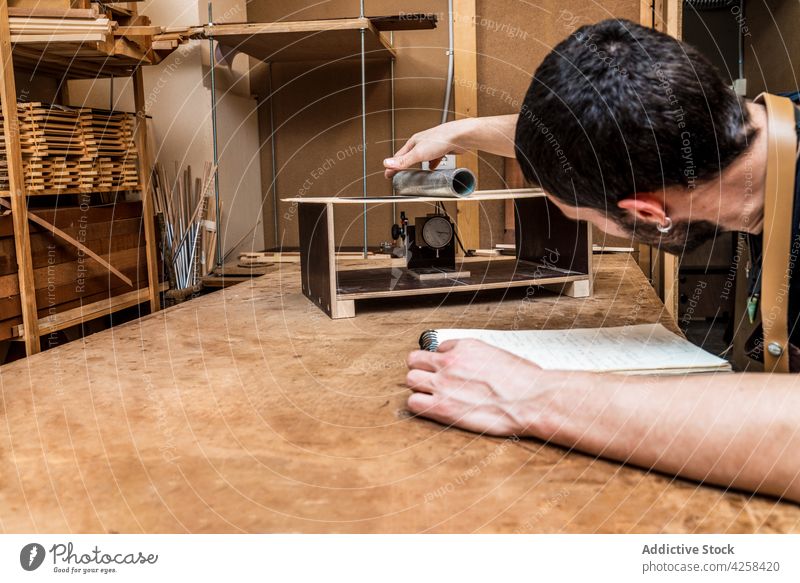 Gitarrenbauer untersucht den Resonanzboden in der Werkstatt Zupfinstrumentenmacher prüfen Spielfigur Zylinder Konzentration Holzarbeiten Beruf Mann