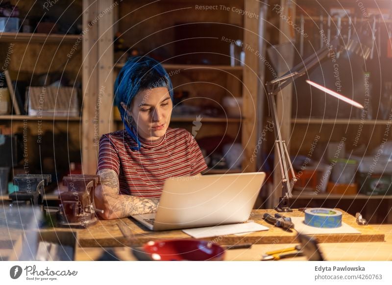 Junge Frau mit Laptop in ihrer Werkstatt diy Hipster Behaarung Tattoos Besitzer Beruf Dienst Kleinunternehmen Mitarbeiter arbeiten Arbeitsplatz Flugzeugwartung