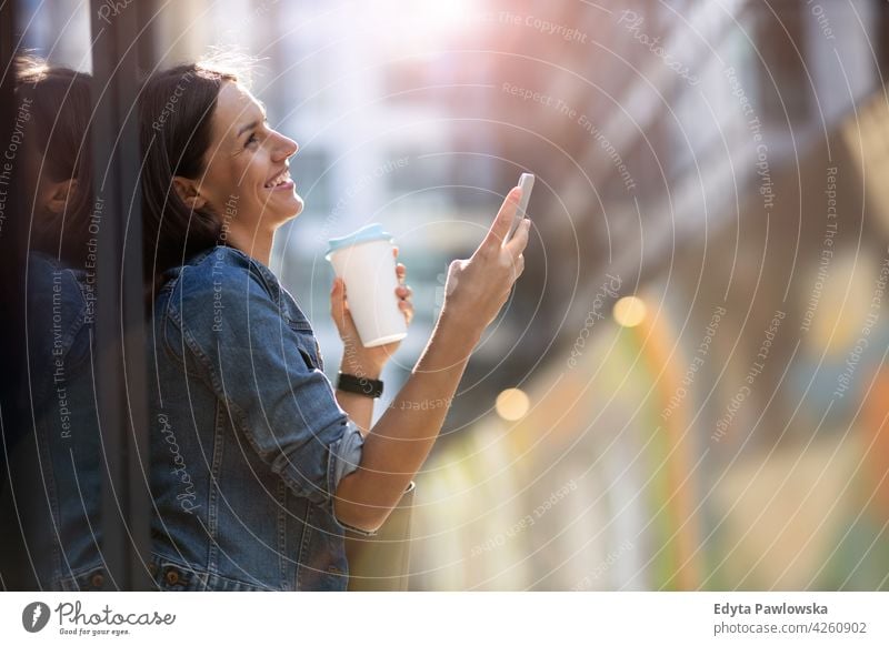 Junge Frau mit Smartphone in einer städtischen Umgebung urban Straße Großstadt aktiv Menschen junger Erwachsener lässig attraktiv Glück Kaukasier genießend