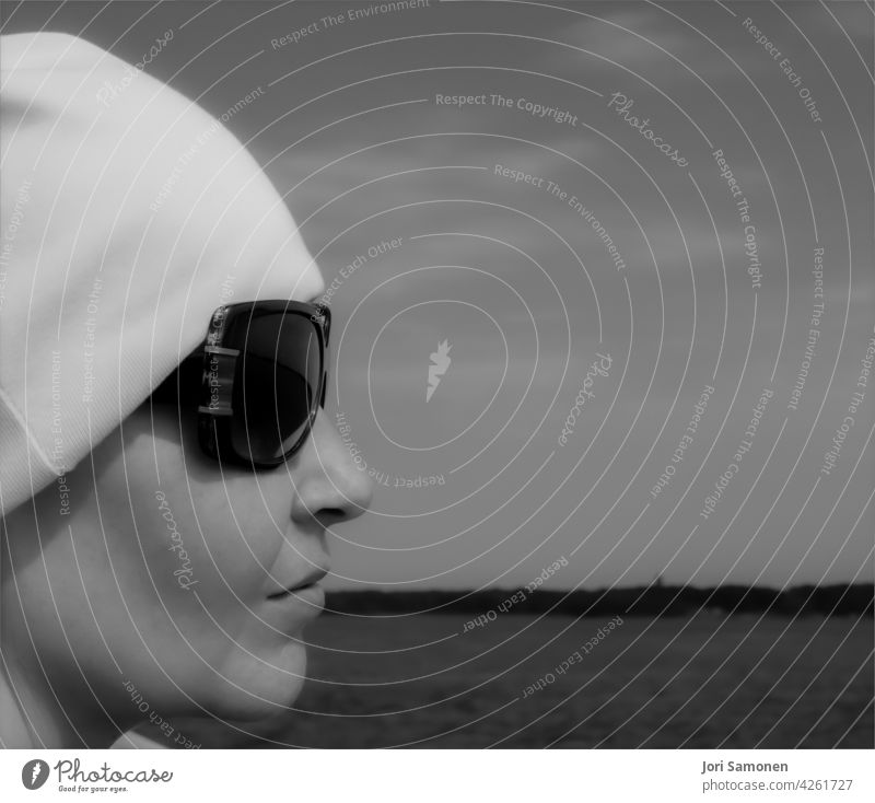 Profil einer Frau mit Sonnenbrille und einer Mütze. Silhouette Gesicht Nase Mund Lippen Mensch feminin Erwachsene 1 Kopf Tag Haut Außenaufnahme Beanie Wasser