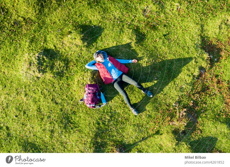 Luftaufnahme einer jungen Wanderin mit einem Rucksack auf dem Rücken liegend auf einer Wiese. Lebensstile Antenne Ferien Frau Wanderer Ausflug Spanien reist