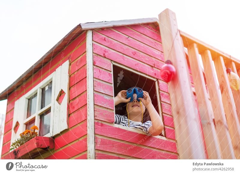 Junge in einem hölzernen Spielhaus schaut durch einen Feldstecher Fernglas Beteiligung Blick Abenteuer Erkundung Holz rot Schweden Haus Baum Baumhaus Sommer
