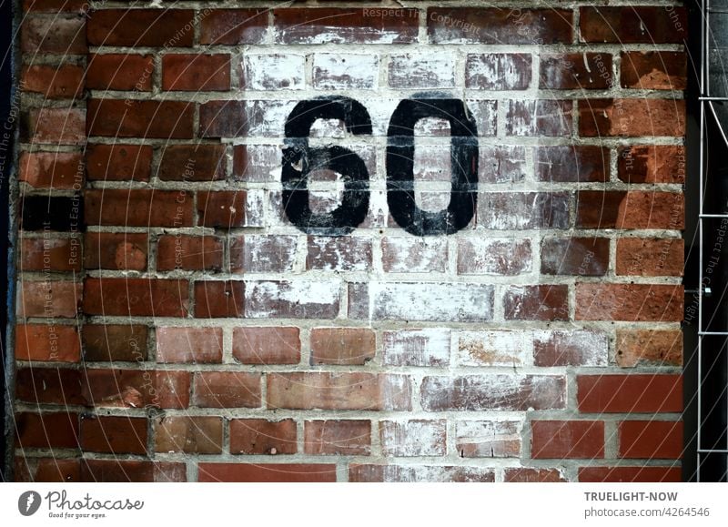 Die Zahl 60 (sechzig) wurde in großen schwarzen Ziffern auf nachlässig weiß getünchtem Quadrat  an die rotbraune Backsteinwand eines alten Gebäudes gemalt und stellt vielleicht eine Hausnummer dar