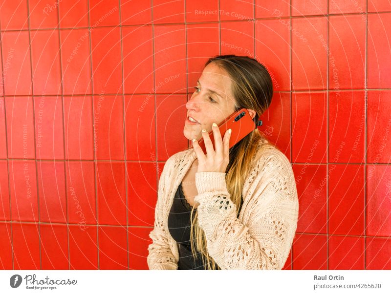 Frau spricht am Handy auf rotem Hintergrund. weiblich mit Telefon, einen Anruf tätigen, Technologie Lebensstil. Person Technik & Technologie Lifestyle