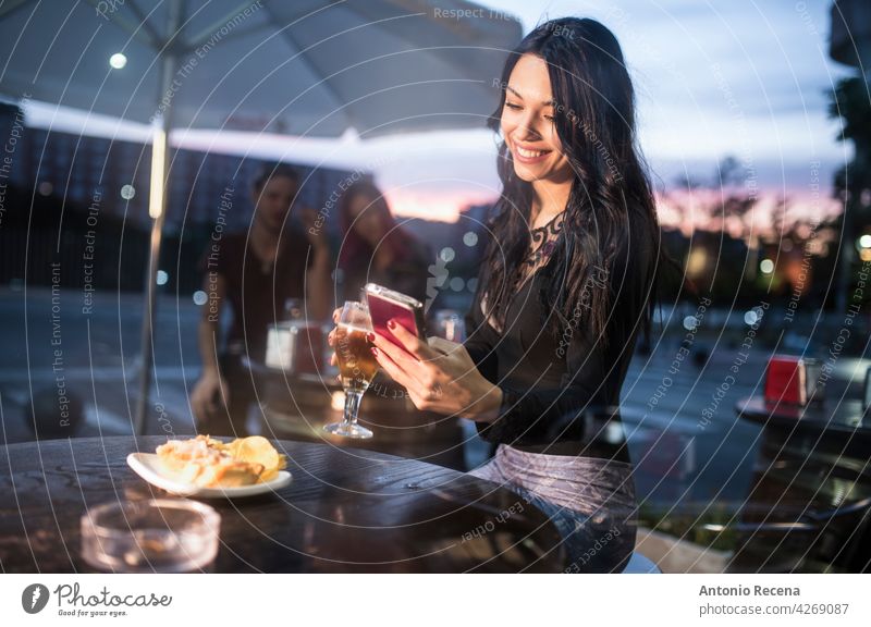 Frau schaut Smartphone in Bar Terrasse beim Bier trinken jung attraktiv 20s Freude Menschen Person Jugend urban Frauen hübsch hübsche Menschen im Freien
