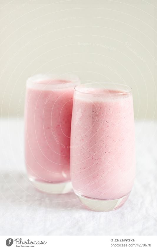 Zwei Gläser mit Erdbeermilchshake. Milchshake Erdbeeren Smoothie Beeren rosa rot melken Glas Minze kalt Sommer Tisch weiß abschließen Selektiver Fokus trinken