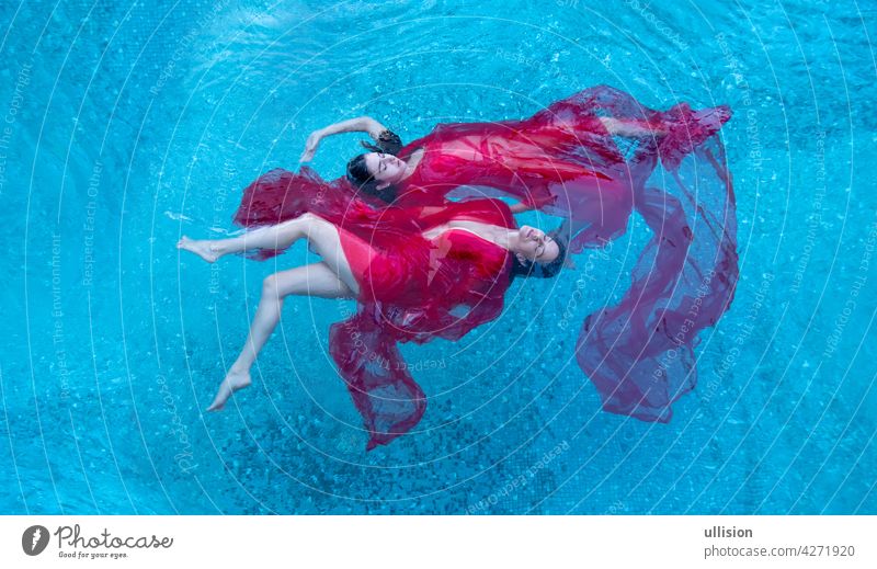 Draufsicht auf eine schöne junge sexy dunkelhaarige Frauen entspannt in rotem Kleid schweben schwerelos elegant im Wasser des Pools, Kopie Raum zwei Schwimmer