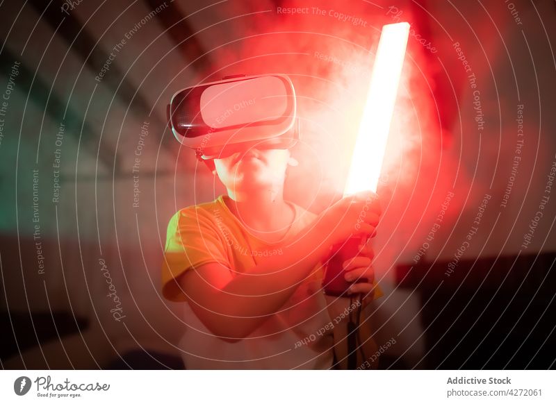 Niedliches Kind in VR-Brille spielt mit Spielzeugschwert Virtuelle Realität spielen Schwert unterhalten Innovation Junge digital Gerät Spaß virtuell lässig