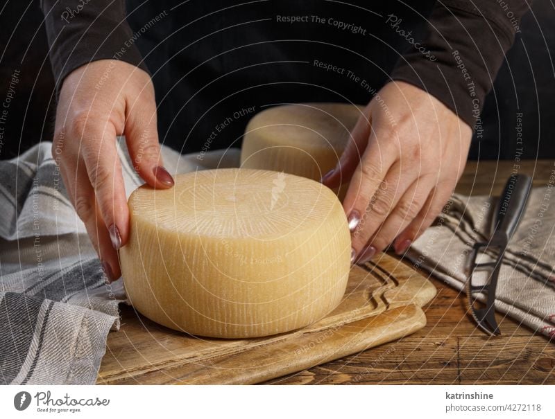 Jemand legt einen Laib frischen, hausgemachten Käse auf ein Holzbrett selbstgemacht Hände Holzplatte setzen hölzern abschließen Spielfigur Italienisch