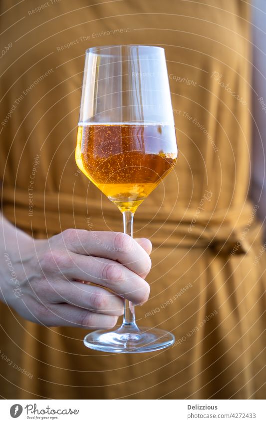 Eine Frau in einem orangefarbenen Kleid hält ein Glas Apfelwein, Nahaufnahme eines Sommergetränks Alkohol trinken Französisch Fotografie Hand im Freien