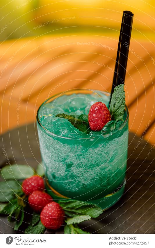 Erfrischender Cocktail mit Himbeeren und Minzblättern Curaçao Likör Gin Passionsfrucht Zitrone Saft Minze dienen Glas kalt Getränk Erfrischung exotisch mischen
