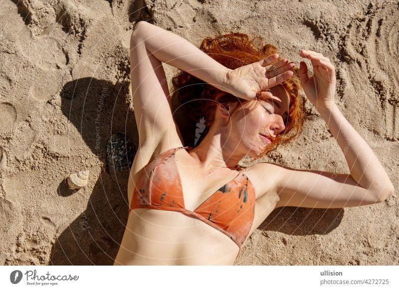 Overhead-Schuss von einem sexy Rothaarige Bikini Frau Rothaarige liegen in der Sonne auf dem Sand am Strand Rotschopf Porträt Haut außerhalb blass verführerisch
