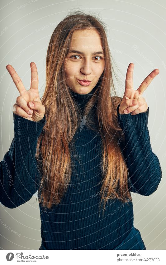 Aufgeregtes Mädchen gestikuliert Friedenszeichen. Porträt in positiver Stimmung. Mädchen macht Sieg Zeichen Geste Kopfschuss Frau Model Person jung Teenager