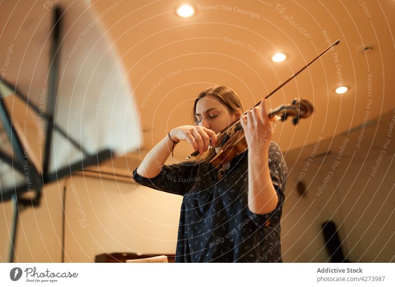 Eine Geigerin spielt klassische Musik in einem Saal Frau Musiker spielen ausführen Probe Instrument Fähigkeit Melodie Klang Augen geschlossen Talent genießen