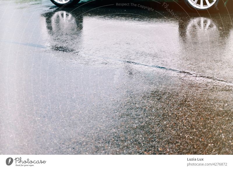 Sommerregen, Alufelgen spiegeln sich in der Nässe auf der Fahrbahn Regen Auto Spiegelung Reflexion & Spiegelung nass Wasser Licht Glanz glänzend Straße Asphalt