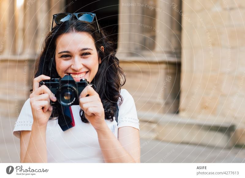 Glückliche Touristin, die mit einer Retro-Kamera Bilder von der Altstadt macht Frau jung Lächeln zahnfarben Fotokamera Fotografie retro Sommer Mädchen Menschen