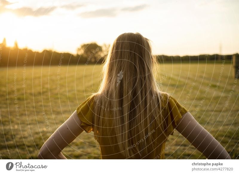 Frau schaut auf Feld im Abendlicht blond Spaziergang Abendsonne Landwirtschaft Pflanzen Getreide Nutzpflanze Wachstum Sommer Menschenleer Ackerbau Natur Ernte