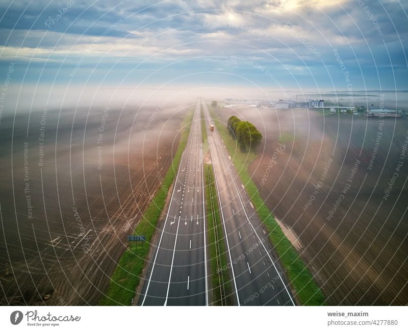 Luftaufnahme einer von Nebel bedeckten Autobahn. Früher nebliger Morgen. Straße im regnerischen Frühling Sommer Felder. Cloud Regen Wetter Verkehr ländlich