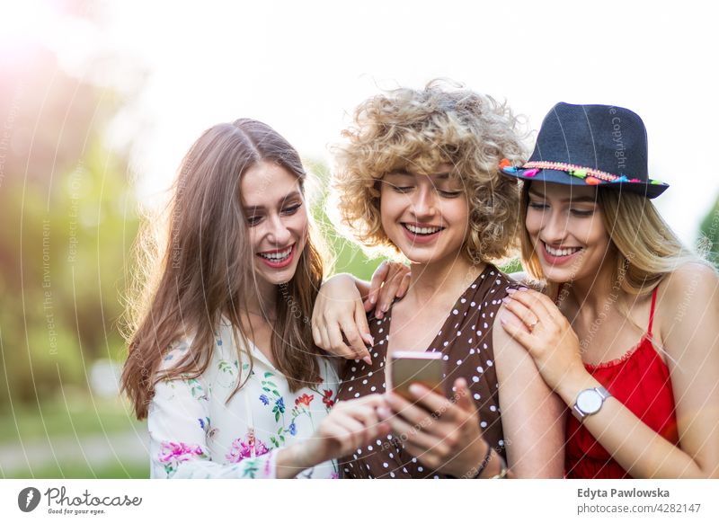 Glückliche junge Frauen haben Spaß mit Smartphone Sonnenuntergang Sommer Menschengruppe Zusammensein lässig schön attraktiv Mädchen drei Personen Freunde