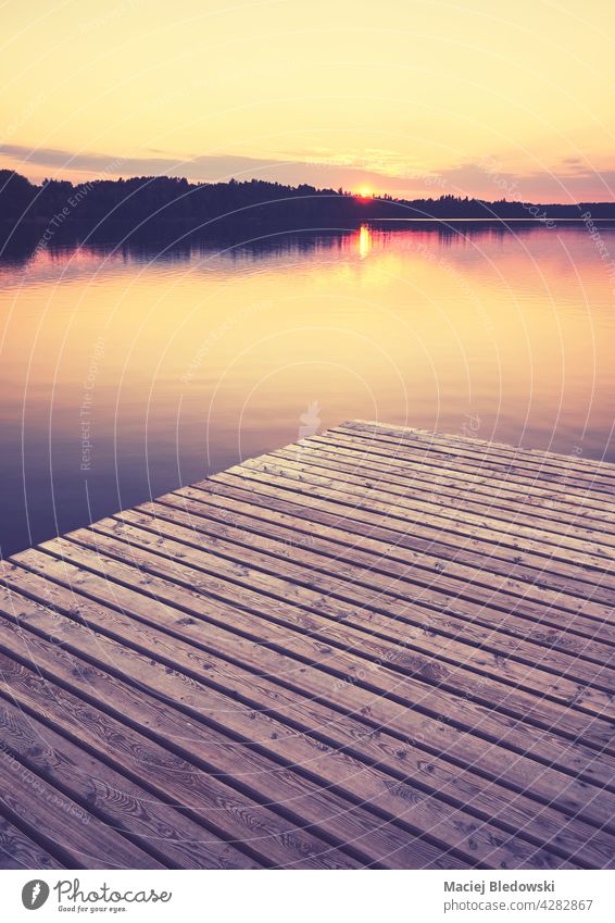 Holzsteg bei goldenem Sonnenuntergang, selektiver Fokus, Farbtonung angewendet, Strzelce Krajenskie, Polen. See Pier im Freien Natur Reflexion & Spiegelung