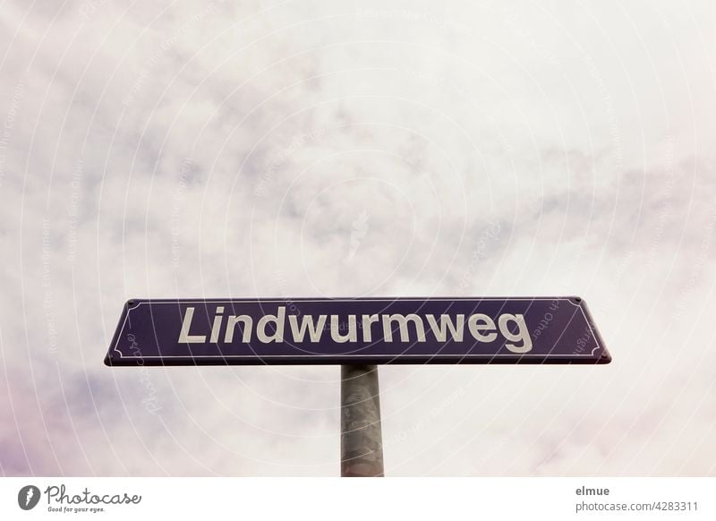 lila Straßennamensschild mit weißer Schrift " Lindwurmweg " vor bewölktem Himmel / Orientierung Straßenschild Straßennamenschild außergewöhnliche Straßennamen