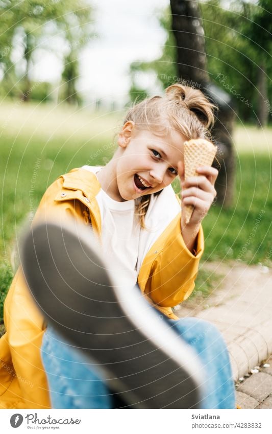 Porträt eines lustigen blonden Teenager-Mädchens mit Eis bei einem Spaziergang im Park. Kind im Freien Sommer Speiseeis gelb Stilrichtung Spaß Glück niedlich