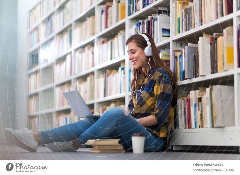 Weibliche College-Studentin sitzt in einer Bibliothek und benutzt einen Laptop genießend Lifestyle jung Erwachsener Menschen eine Person lässig Kaukasier