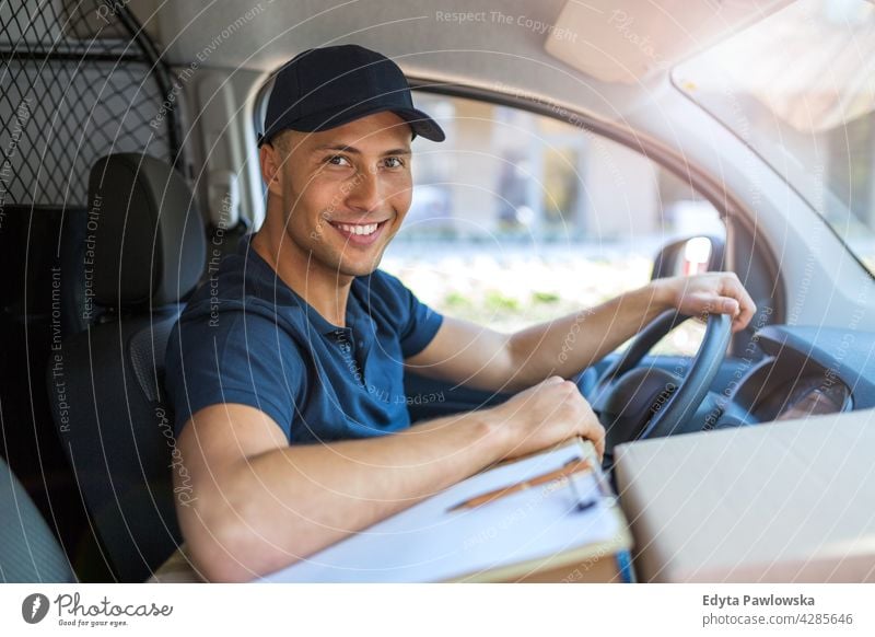 Zusteller in einem Lieferwagen sitzend Kleintransporter PKW Fahrer Lastwagen Menschen junger Erwachsener Mann männlich Lächeln Glück blauer Kragen Kurier