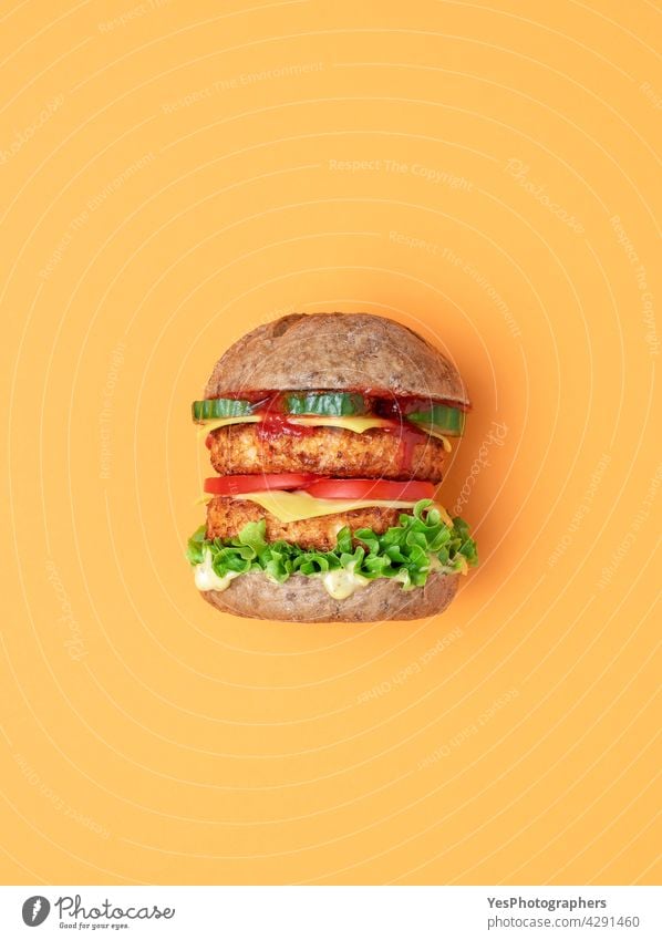 Veggie-Burger Draufsicht isoliert auf einem orangefarbenen Hintergrund. oben alternativ Brot Brötchen Käse Cheeseburger Farbe Konsumverhalten Küche ausschneiden