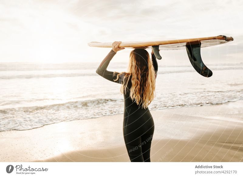 Anonyme Surferin am Strand mit Surfbrett stehend Frau Natur Sonnenuntergang winken im Freien Neoprenanzug Meeresküste Brandung Sportlerin MEER Surfen Hobby
