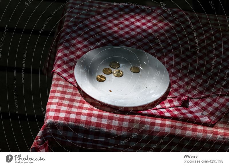 Ein Teller mit Münzen auf dem Tisch fordert die Benutzer der Toilette zum Bezahlen auf Tischdecke Geld WC Schatten Kleingeld Wechselgeld Bezahlung Gebühr Cent