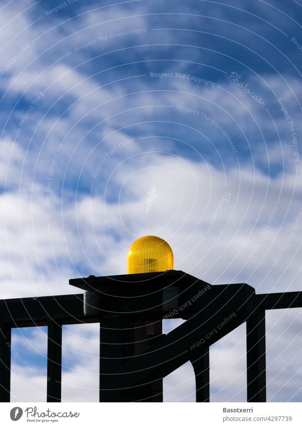 Gelbes Warnlicht an einem automatischen Tor, im Hintergrund blauer Himmel und weisse Wolken Blinklicht gelb Zaun Gatter automatisches Tor Warnung Gefahr Gitter