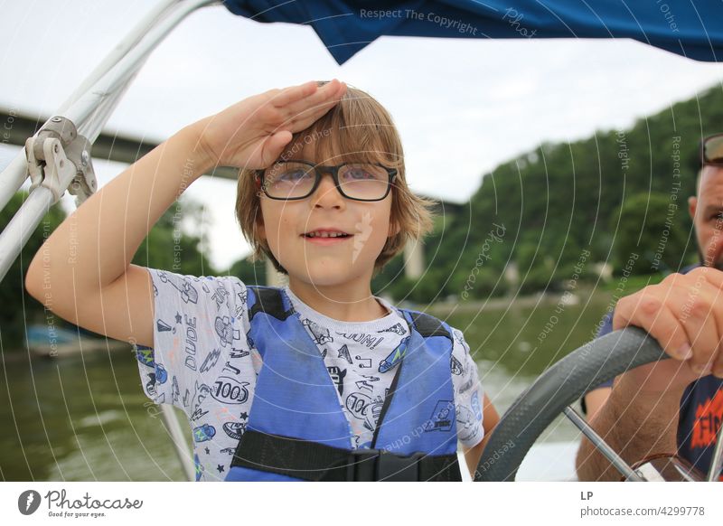 Kind mit Brille, das fröhlich zum Horizont schaut und wie ein Kapitän salutiert Mensch Gefühle Eltern Sinnesorgane Meditation Windstille Geschwister