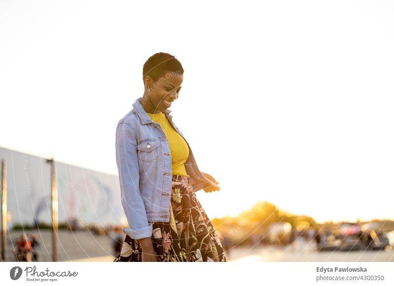 Lächelnde junge Frau genießt die Natur bei Sonnenuntergang Afro-Look stolz echte Menschen Stadtleben Afroamerikaner Afrikanisch Schüler schwarz Ethnizität