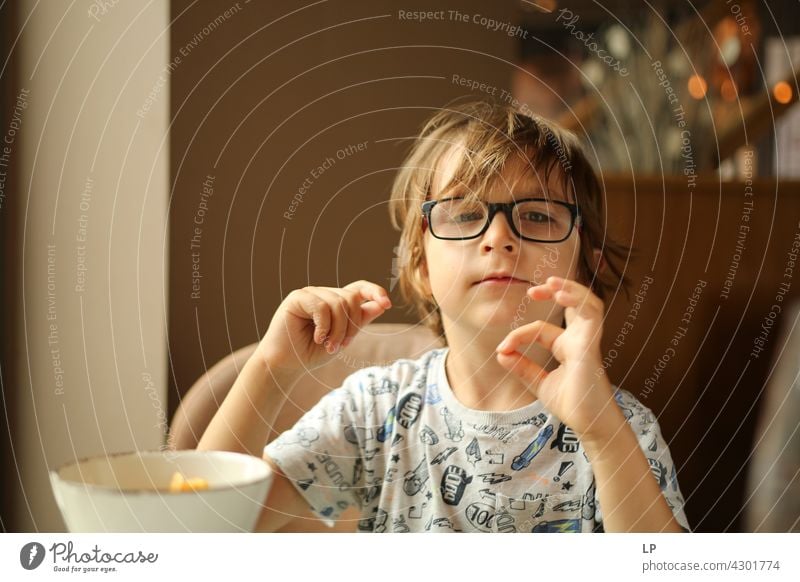 Kind mit Brille schaut neugierig in die Kamera und spielt mit seinen Fingern Stil Design Mensch Gefühle Farbfoto Eltern Kontrast Hintergrund neutral