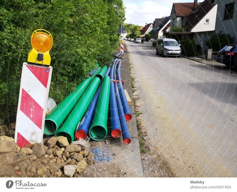 Grüne und blaue Rohre aus Kunststoff an einer Baustelle mit Warnbake in Oerlinghausen bei Bielefeld am Hermannsweg im Teutoburger Wald in Ostwestfalen-Lippe