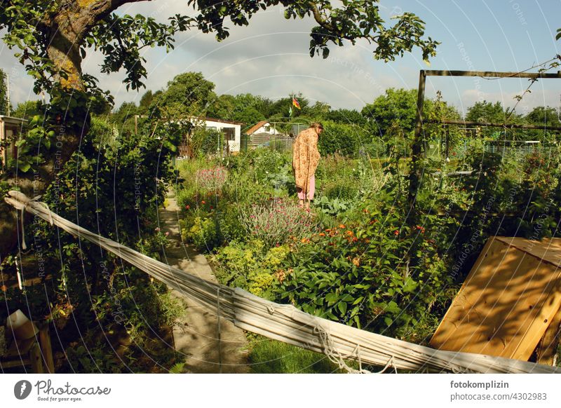 Junge Frau steht inmitten ihrem Blumen- und Gemüsegarten Garten selbstversorgung gärtnern erholung Schrebergarten kleingarten biologisch schrebergarten ruhe