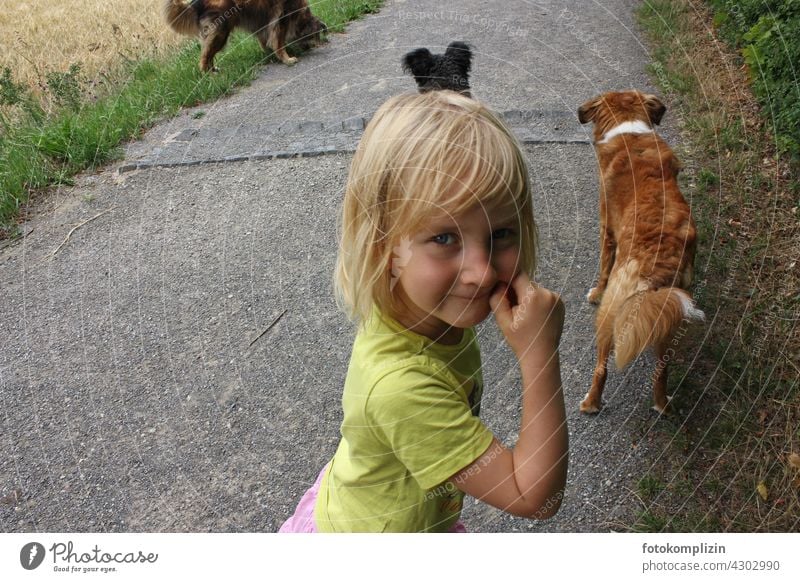 verschmitzter Blick eines Kind mit Hunden im Hintergrund fröhlich Haustier Haushund Tierliebe Weg Gassi Gassi gehen im freien Kindheit Blick in die Kamera